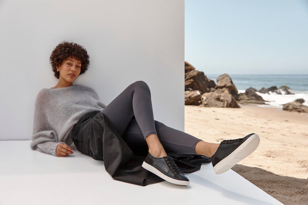 Woman relaxing on a beach wearing Vionic Winny black leather sneakers
